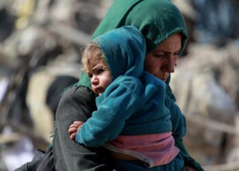 Eine palästinensische Frau trägt ein Baby, während Familien nach israelischen Luftangriffen in den frühen Morgenstunden des 18. März 2025 auf den Norden und andere Teile des Gazastreifens den östlichen Teil des Gazastreifens an der Grenze zu Israel verlassen. Die israelische Armee forderte die Bewohner Gazas am 18. März auf, Gebiete in der Nähe der Grenze zu evakuieren, nachdem sie in der Nacht eine Welle tödlicher Angriffe gestartet hatte, die intensivsten seit Beginn der Waffenruhe im Januar. Die Rettungskräfte von Gaza gaben an, dass die Zahl der Todesopfer durch die massive israelische Offensive im gesamten palästinensischen Gebiet auf über 220 Menschen, darunter auch Kinder, gestiegen sei. (Foto: Bashar TALEB / AFP)